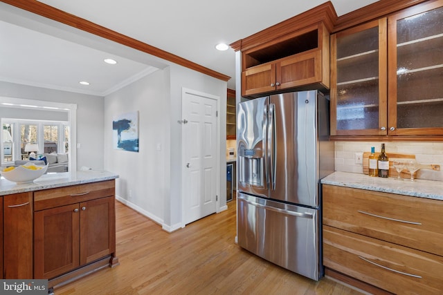 kitchen with tasteful backsplash, light stone countertops, light hardwood / wood-style floors, and stainless steel fridge with ice dispenser