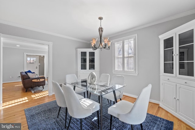 dining area with ornamental molding, a chandelier, and light hardwood / wood-style floors