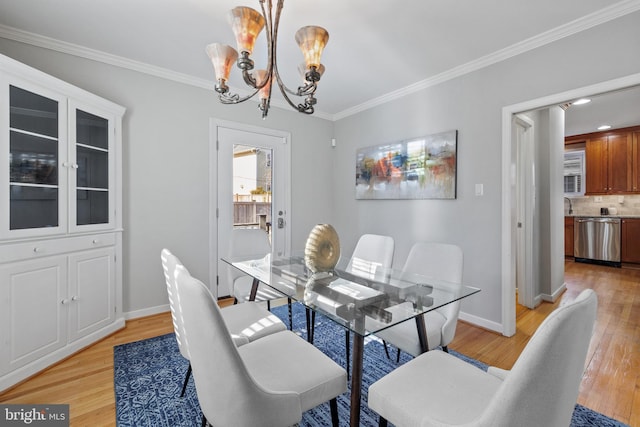 dining room featuring ornamental molding, a notable chandelier, and light hardwood / wood-style floors