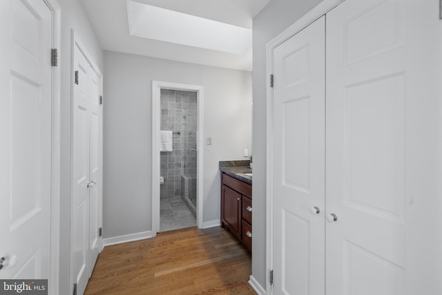 bathroom featuring vanity, hardwood / wood-style floors, a shower with shower door, and a skylight