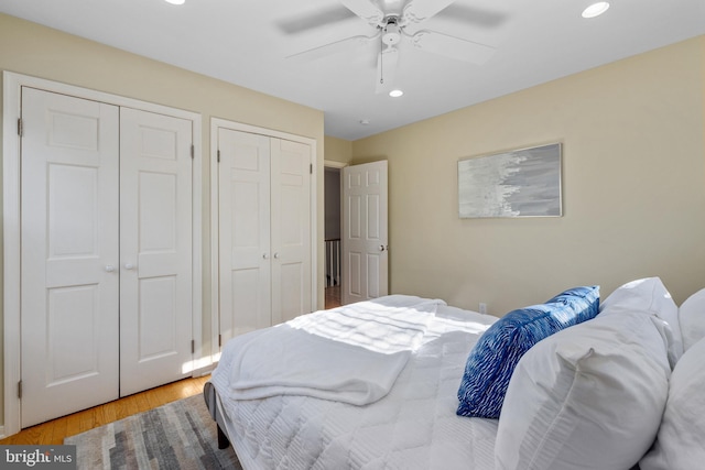 bedroom with multiple closets, ceiling fan, and light hardwood / wood-style flooring