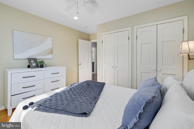 bedroom with wood-type flooring, two closets, and ceiling fan