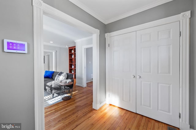 hallway with ornamental molding and light wood-type flooring