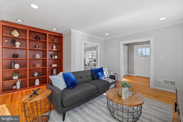 living room with crown molding, plenty of natural light, and light wood-type flooring