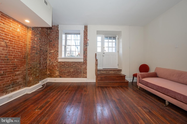 unfurnished living room with brick wall and dark hardwood / wood-style flooring