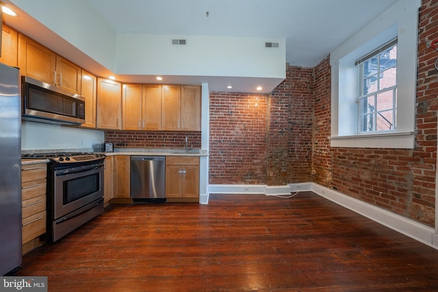 kitchen with brick wall, appliances with stainless steel finishes, sink, and dark hardwood / wood-style flooring