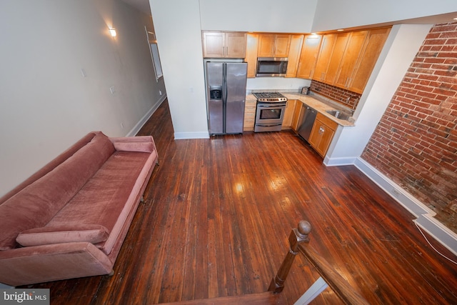 kitchen with stainless steel appliances, brick wall, dark hardwood / wood-style floors, and sink