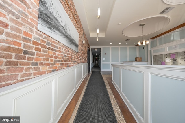 hallway featuring brick wall and dark wood-type flooring