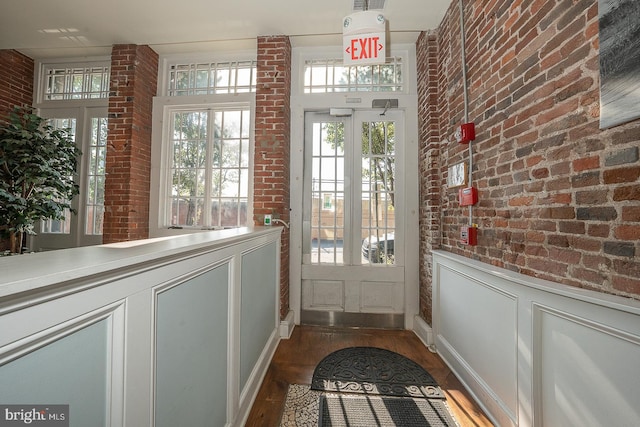 doorway featuring dark wood-type flooring and brick wall