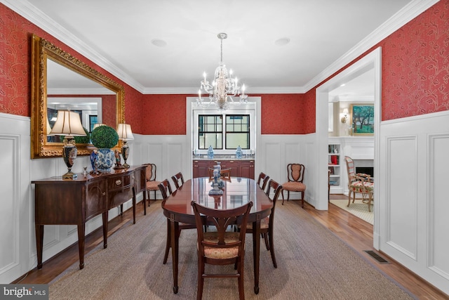 dining area with an inviting chandelier, crown molding, and hardwood / wood-style floors