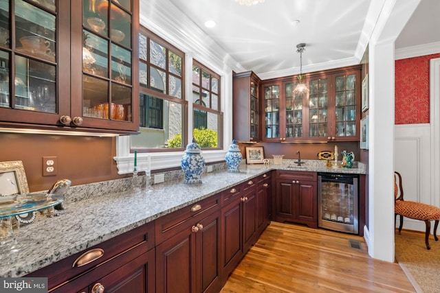 bar featuring pendant lighting, sink, wine cooler, ornamental molding, and light stone countertops