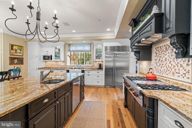 kitchen featuring white cabinetry, built in appliances, a raised ceiling, and sink