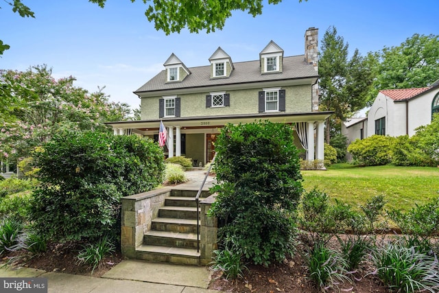 view of front of home with covered porch and a front lawn