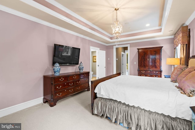 carpeted bedroom featuring ensuite bath, ornamental molding, a tray ceiling, and a notable chandelier