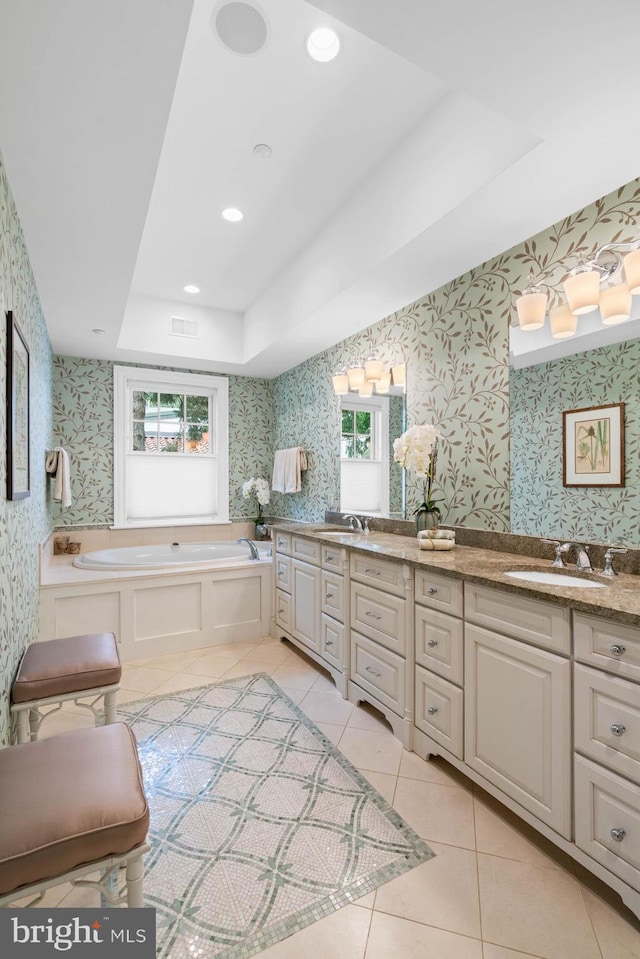 bathroom featuring tile patterned flooring, vanity, a raised ceiling, and a tub to relax in