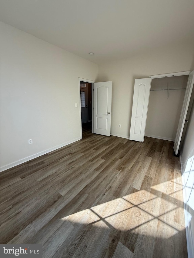 unfurnished bedroom featuring wood-type flooring and a closet