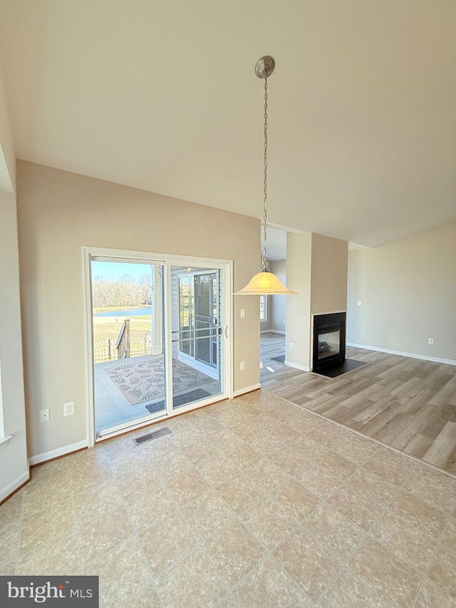 unfurnished living room featuring a multi sided fireplace and a wealth of natural light