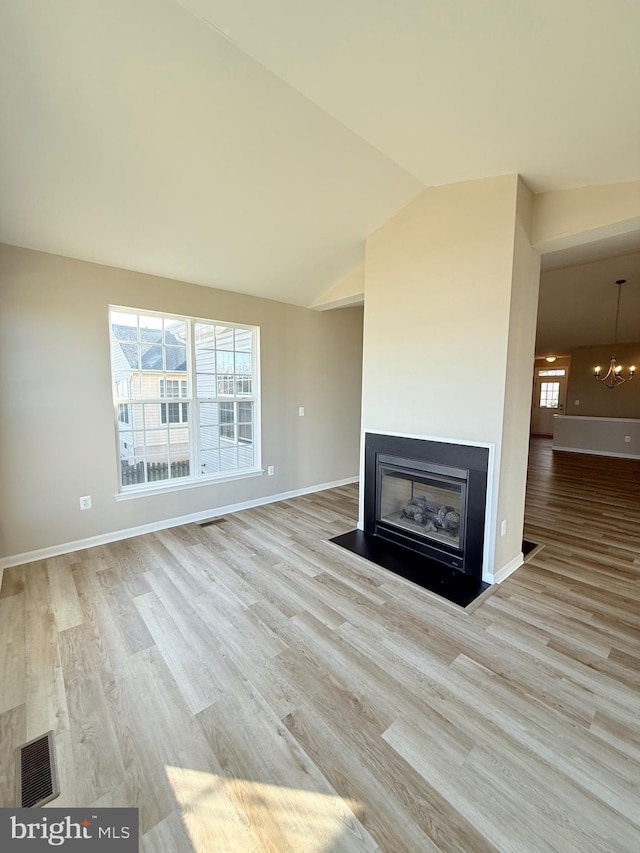 unfurnished living room featuring lofted ceiling, a notable chandelier, and light hardwood / wood-style flooring