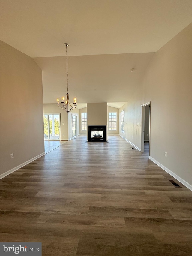 unfurnished living room featuring dark hardwood / wood-style flooring, high vaulted ceiling, a chandelier, and a multi sided fireplace