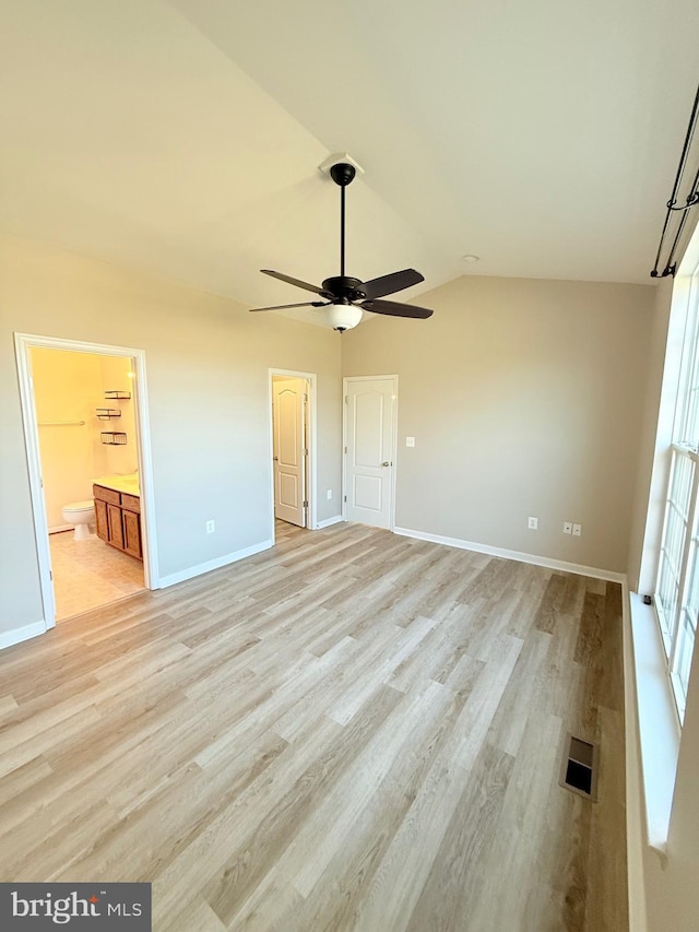 unfurnished bedroom with ensuite bathroom, lofted ceiling, ceiling fan, and light hardwood / wood-style flooring