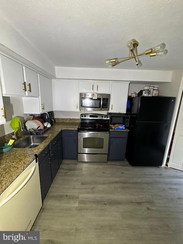 kitchen with appliances with stainless steel finishes, sink, white cabinets, dark wood-type flooring, and a textured ceiling