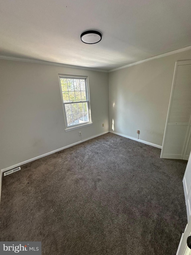 unfurnished room with dark colored carpet and ornamental molding