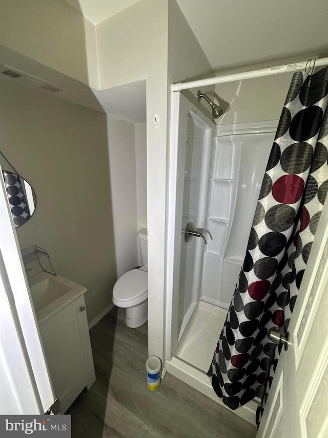 bathroom featuring a shower with curtain, wood-type flooring, toilet, and vanity