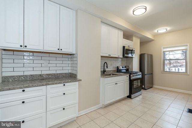 kitchen featuring stainless steel appliances, sink, dark stone counters, and white cabinets