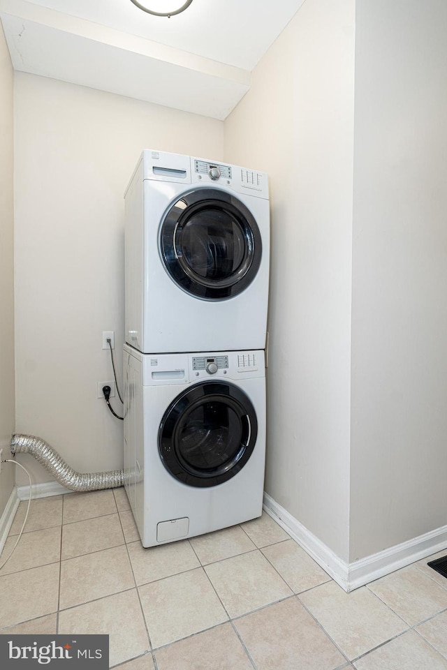 laundry area featuring stacked washer and clothes dryer and light tile patterned flooring