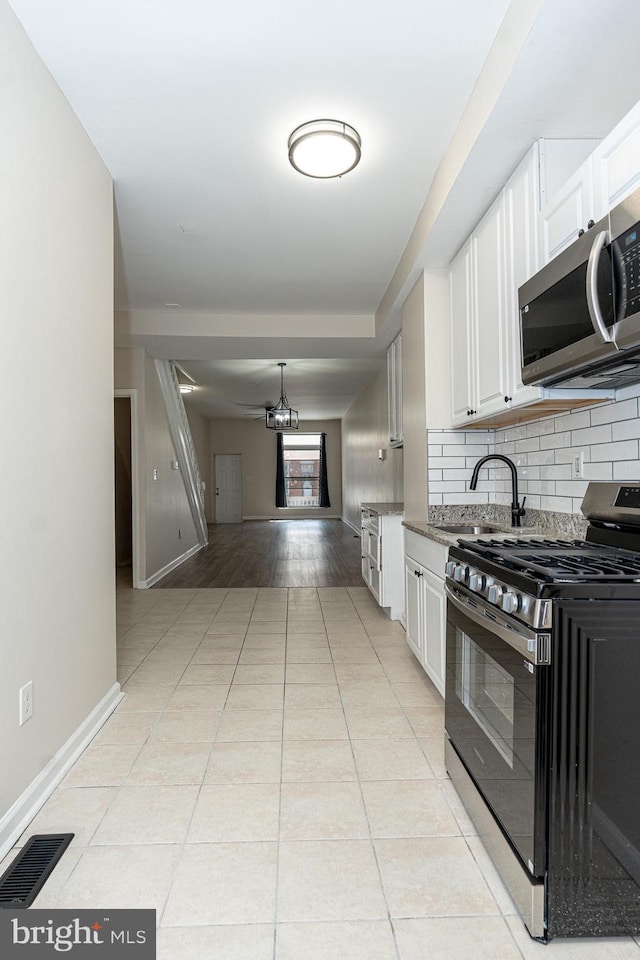 kitchen with white cabinetry, range with gas stovetop, sink, and decorative backsplash