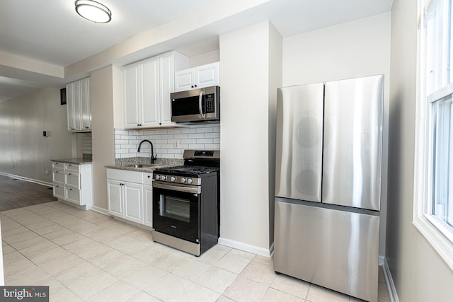 kitchen with sink, white cabinetry, appliances with stainless steel finishes, light stone countertops, and decorative backsplash