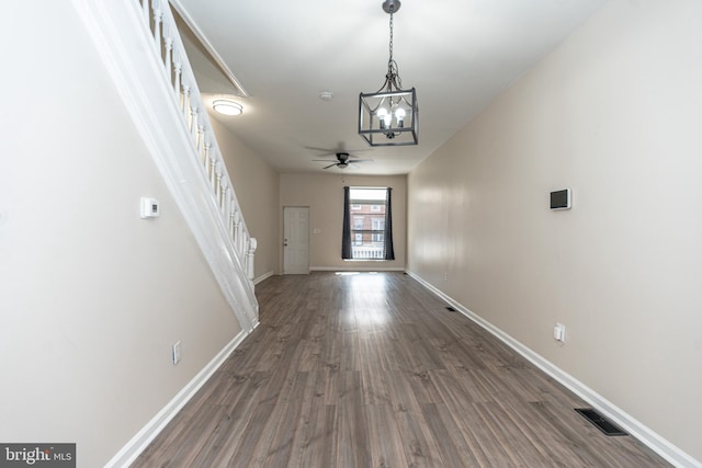 interior space with dark wood-type flooring and ceiling fan with notable chandelier