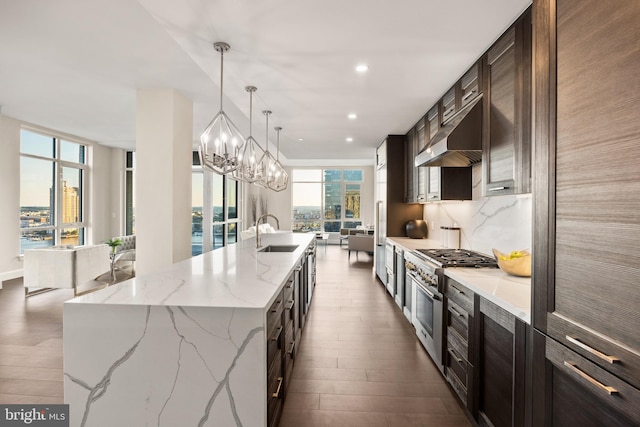 kitchen with sink, pendant lighting, a large island, high end stove, and backsplash