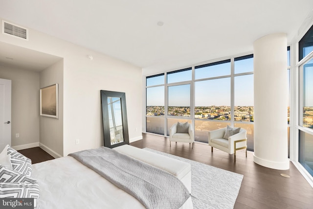 bedroom featuring a wall of windows and dark hardwood / wood-style flooring