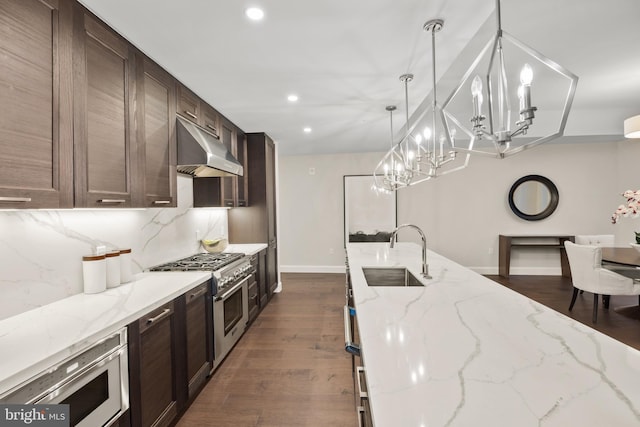 kitchen featuring pendant lighting, sink, appliances with stainless steel finishes, range hood, and light stone counters