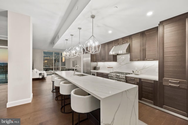 kitchen featuring dark hardwood / wood-style floors, pendant lighting, ventilation hood, sink, and a spacious island