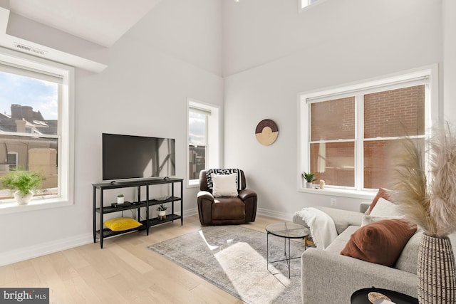 living room with a towering ceiling and light wood-type flooring