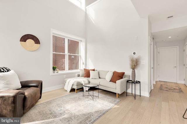 living room with a high ceiling and light wood-type flooring