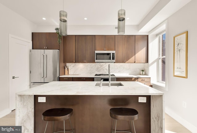 kitchen with backsplash, decorative light fixtures, a kitchen breakfast bar, and appliances with stainless steel finishes