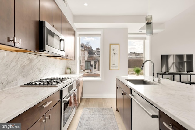 kitchen with pendant lighting, sink, dark brown cabinets, stainless steel appliances, and decorative backsplash