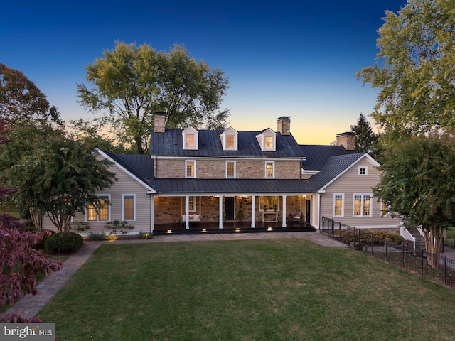 back house at dusk featuring a yard