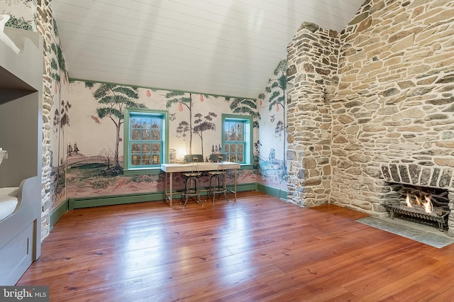 interior space with hardwood / wood-style flooring, a fireplace, vaulted ceiling, and a baseboard heating unit