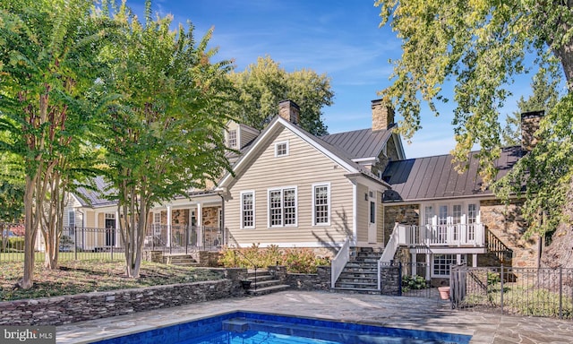 rear view of house featuring a fenced in pool and a patio area