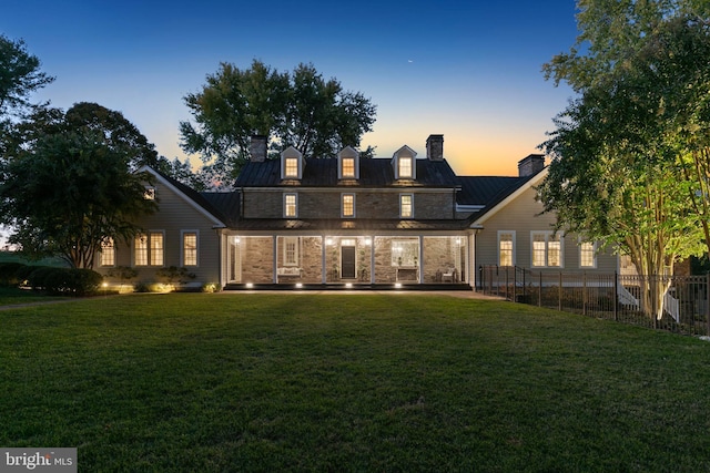 back house at dusk with a lawn