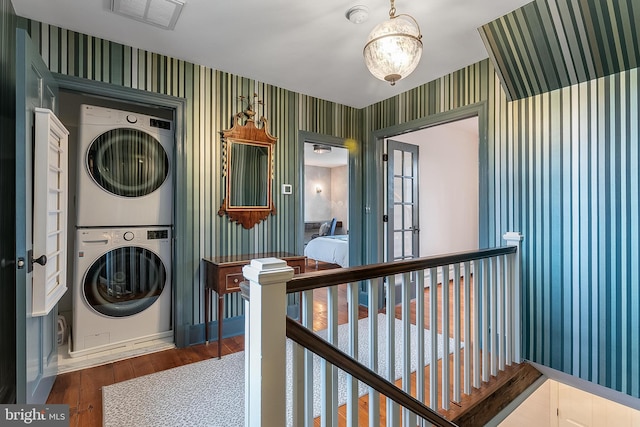 washroom featuring hardwood / wood-style flooring and stacked washer and clothes dryer