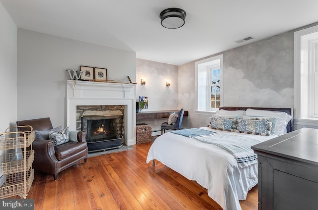 bedroom with hardwood / wood-style flooring and a high end fireplace