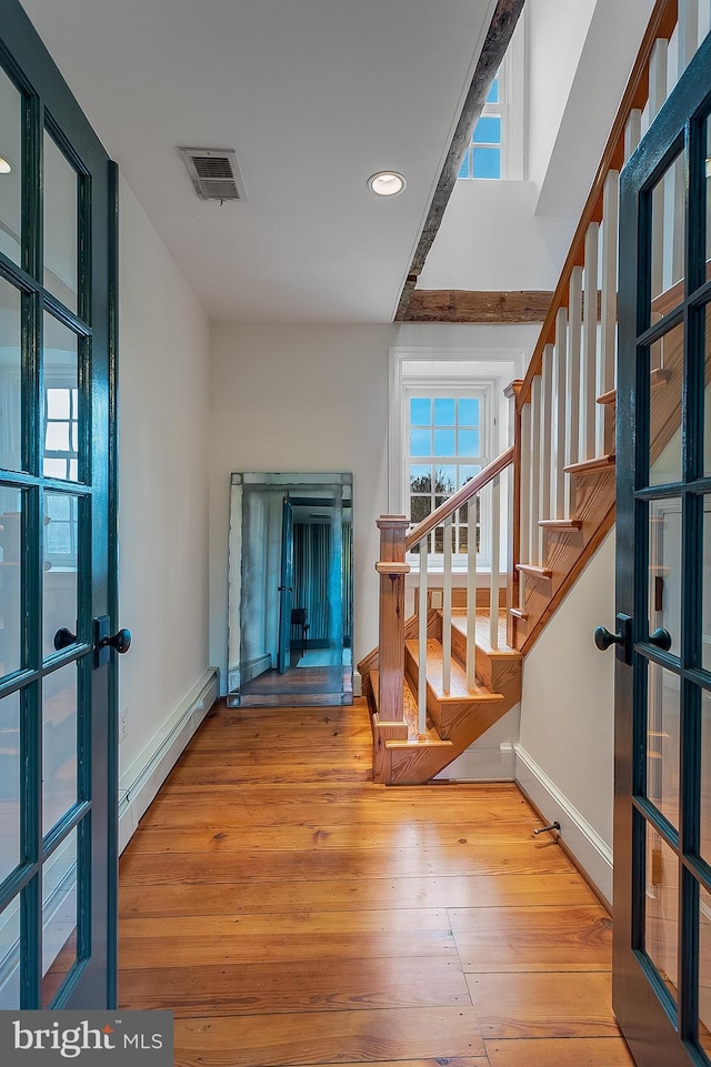 foyer entrance featuring a baseboard heating unit, french doors, and light wood-type flooring