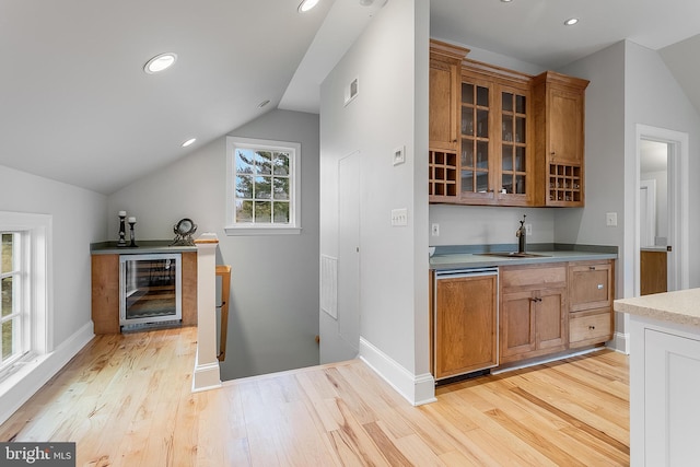 bar with sink, dishwashing machine, vaulted ceiling, and light hardwood / wood-style flooring