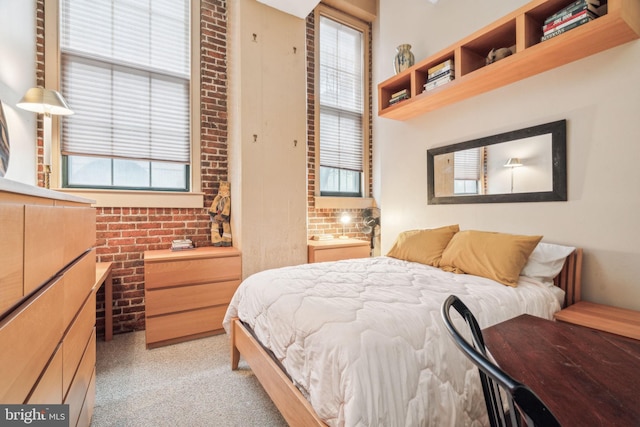 bedroom with multiple windows, brick wall, and light carpet