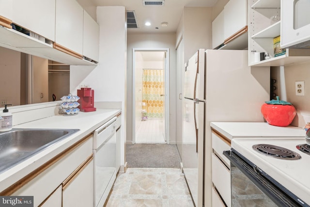 kitchen with white appliances, sink, light carpet, and white cabinets